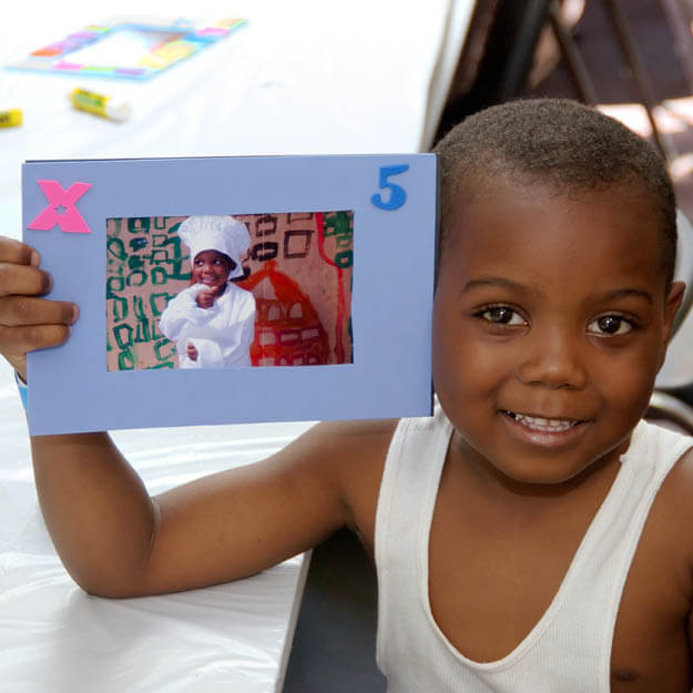 200s photo of child holding a photo of himself dressed up as a chef