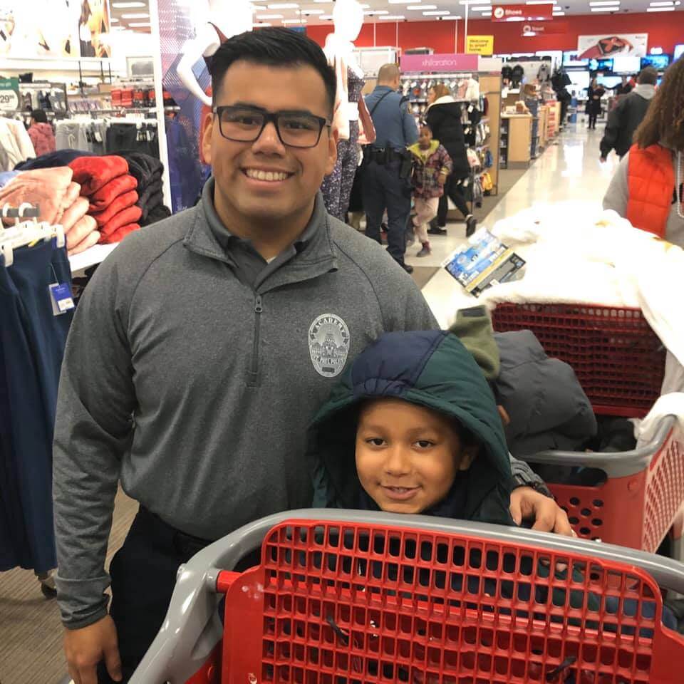 Police officer and young boyshopping at Target, smiling at the camera.