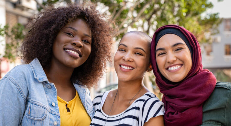 three happy multiethnic young women smiling and looking a the camera