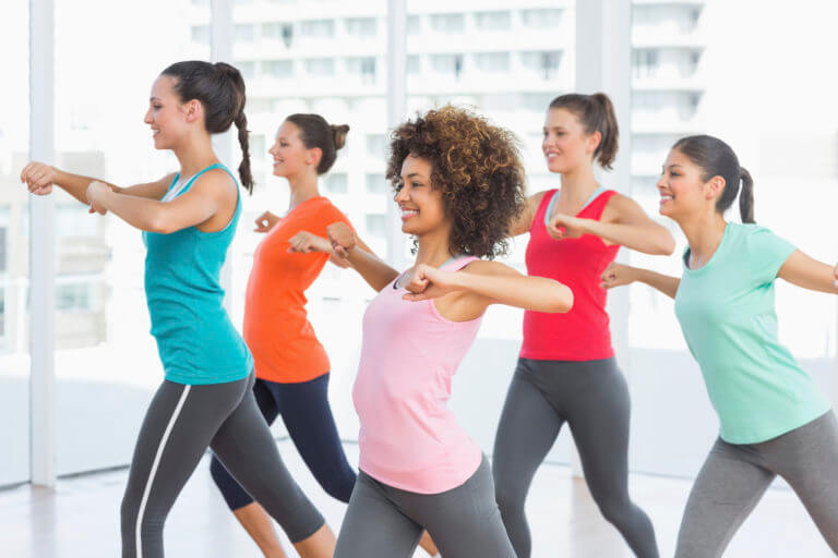 Multicultural group of women doing a dance based exercise class