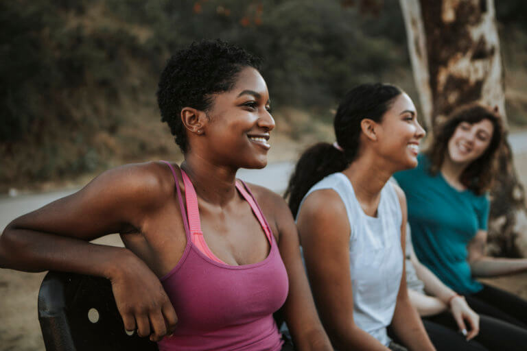 Multicultural young women friends relaxing on a park bench