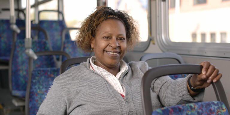 Monique smiling at camera on MetroTransit bus, wearing her work uniform