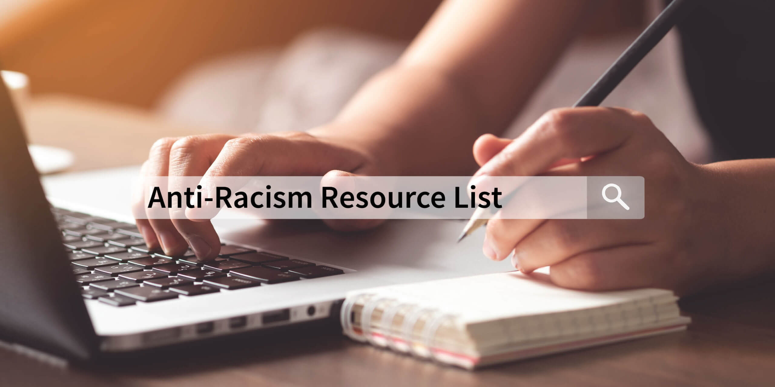 close up photo of hands typing on a keyboard and posed to take notes in a small notebook. Overlay of a search bar with the words "Anti-Racism Resource List" typed inside.