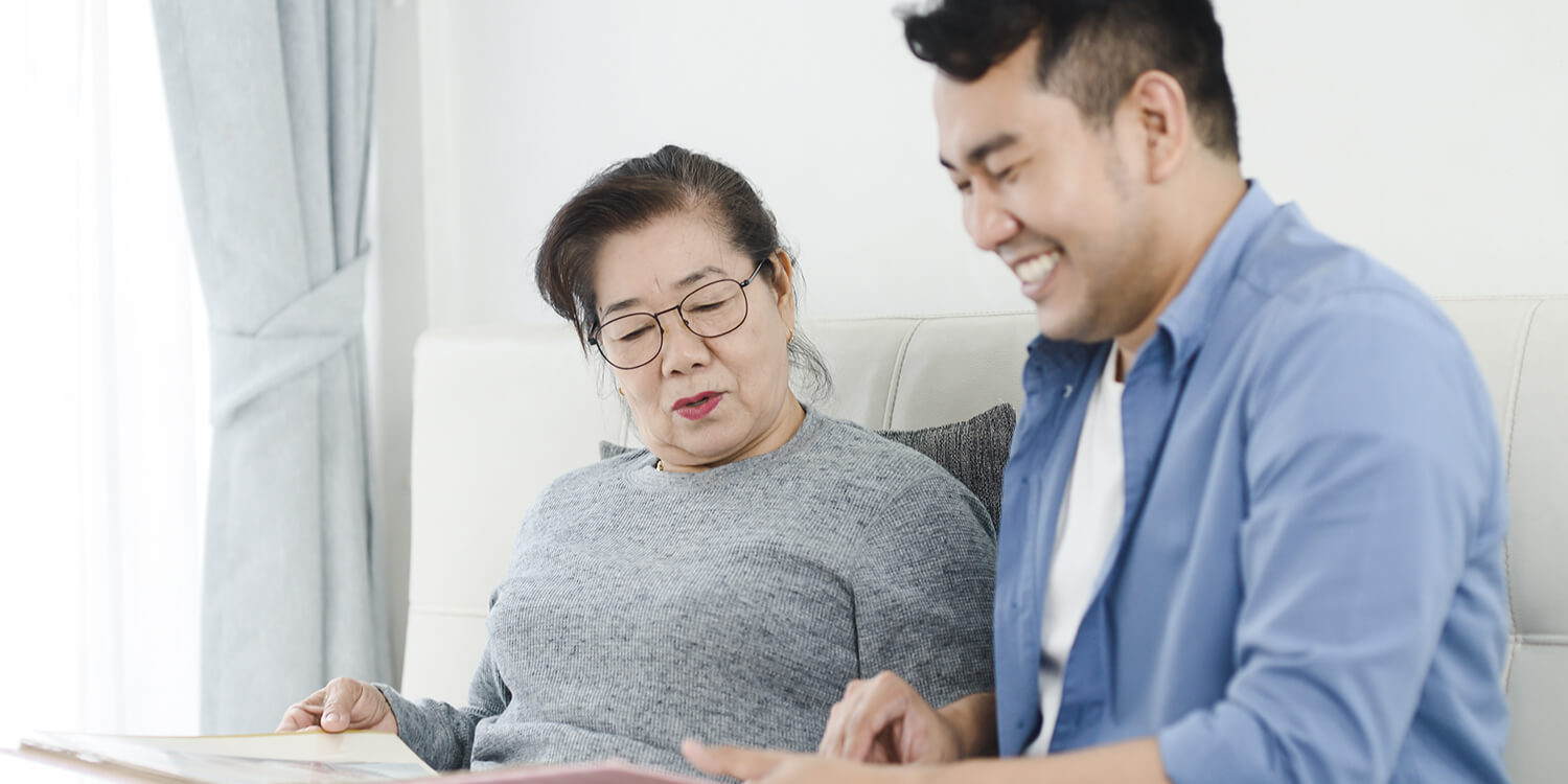 Asian man and his mother looking at photo album together