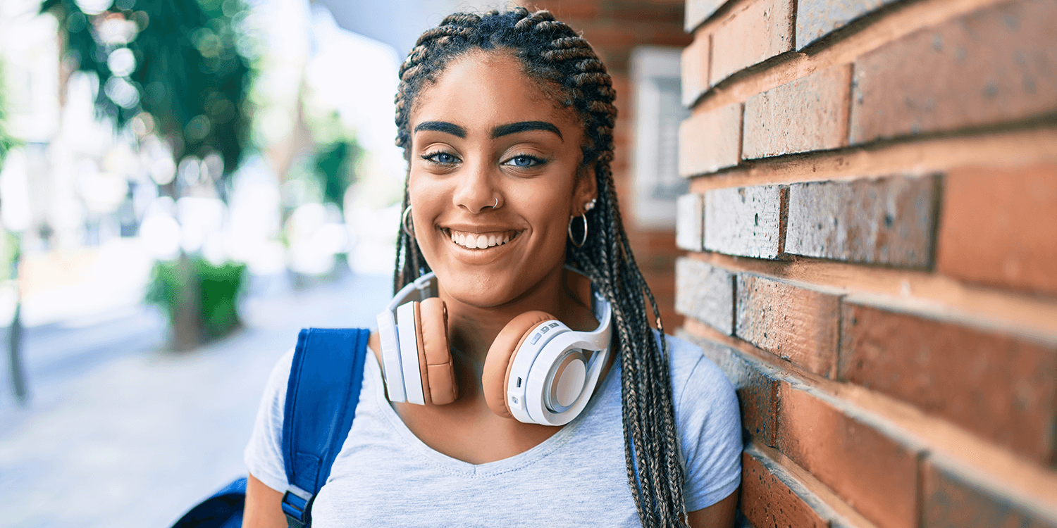 Young african american student woman smiling happy leaning on the wall at the university campus