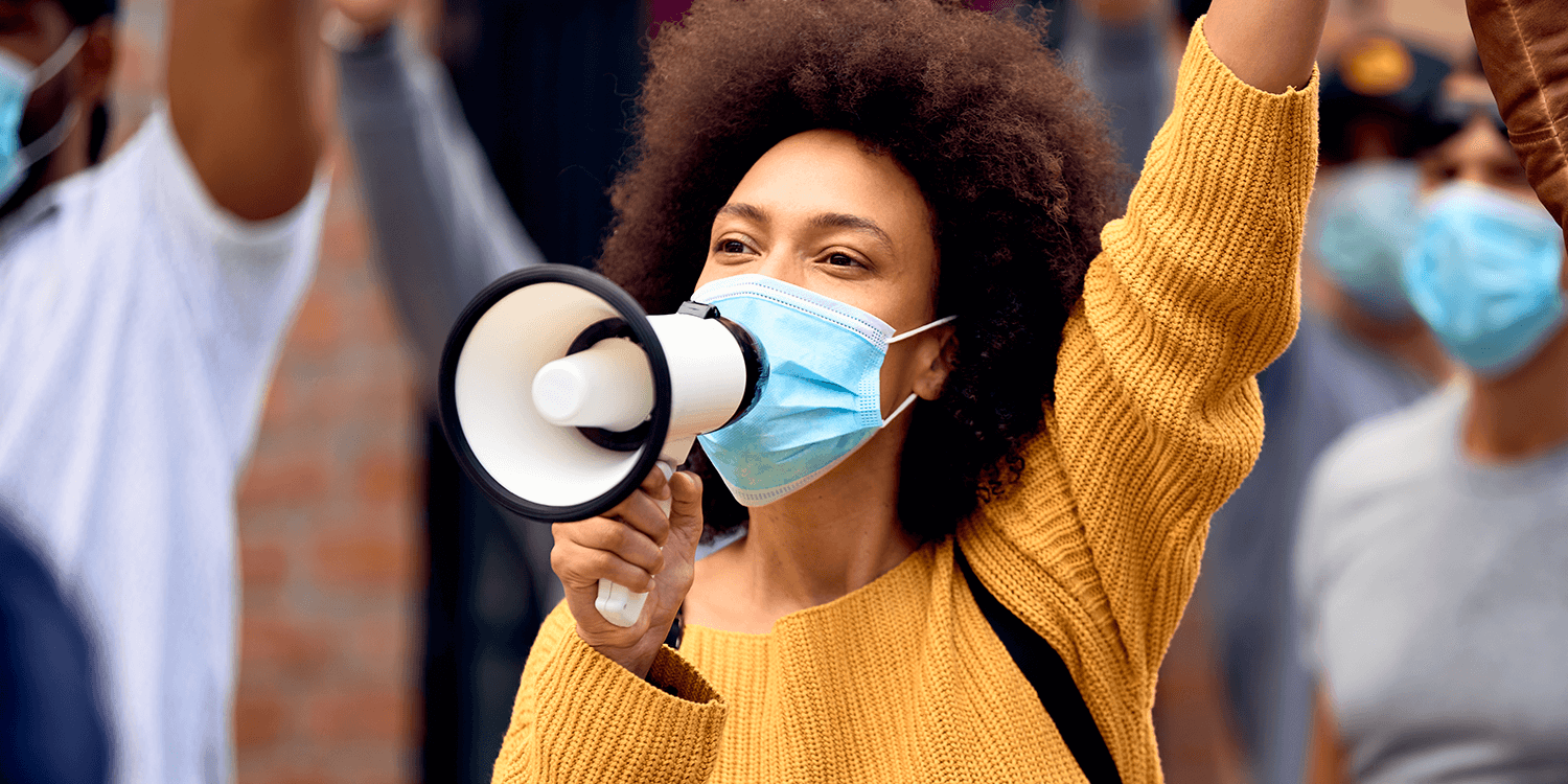 Young African American woman shouting through megaphones at protest